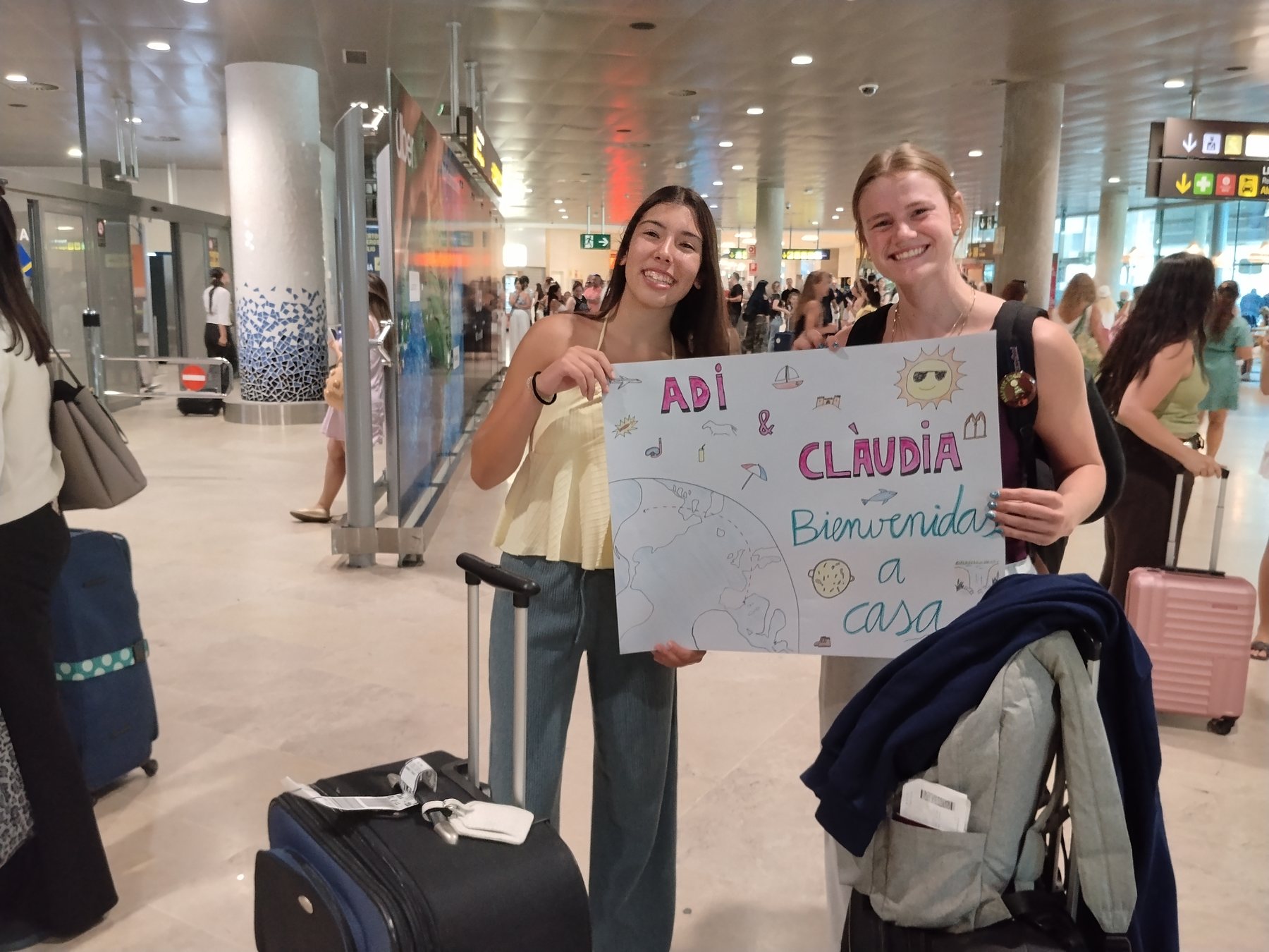 Addilyn and her exchange partner Clàudia at the Valencia airport, holding a hand-drawn welcome sign
